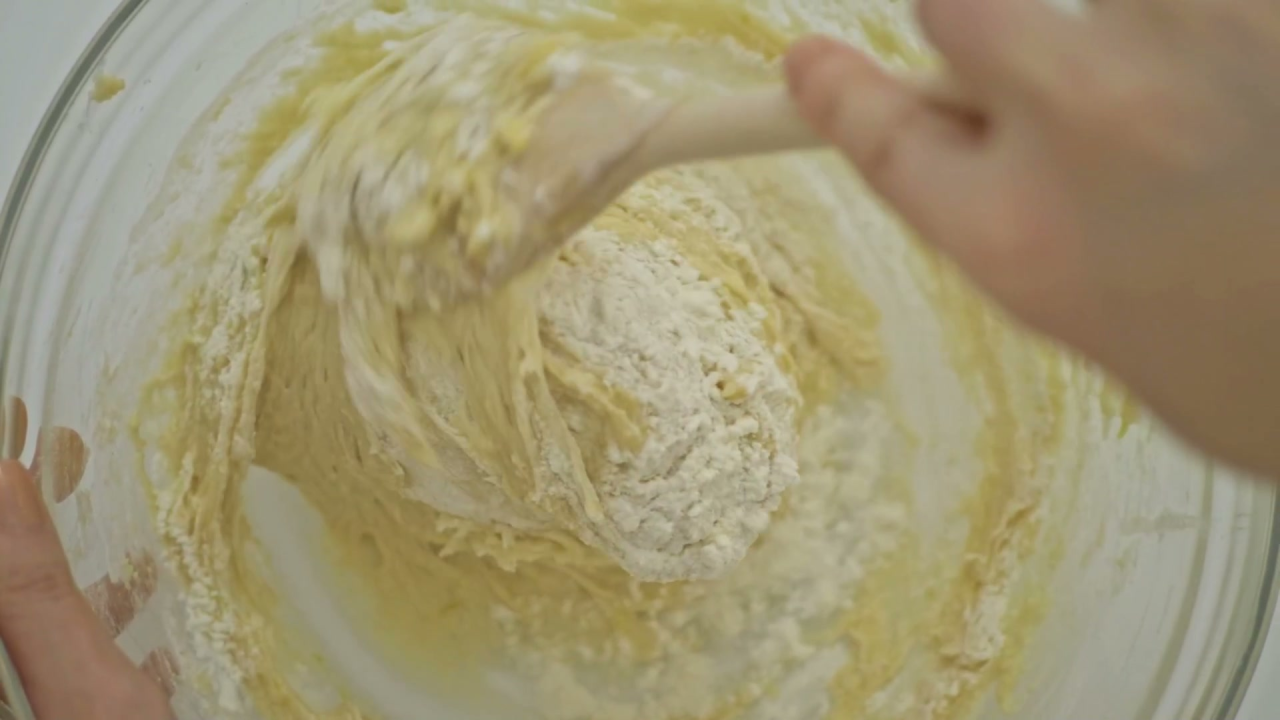 Overhead view of mixing muffin batter in a ceramic bowl with a wooden spoon